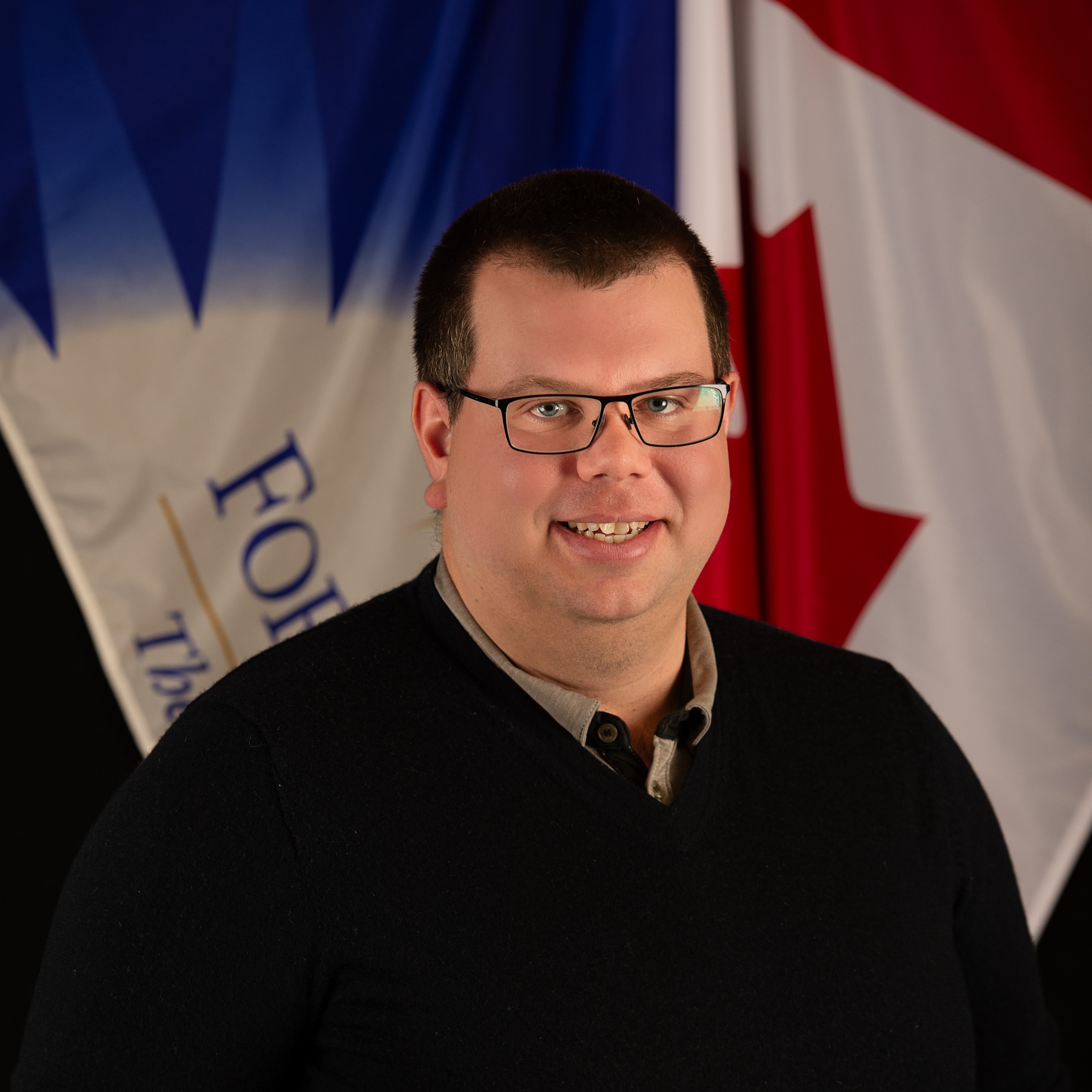 Ryan poses in front of City and Canadian flag.