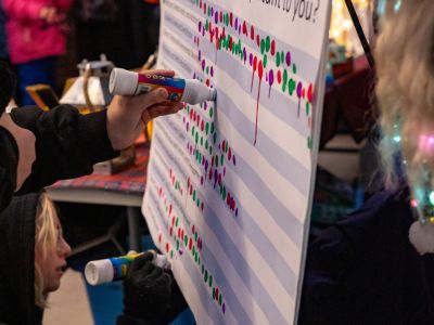 A person uses a bingo dabber to vote on communities priorities at the Santa Parade.