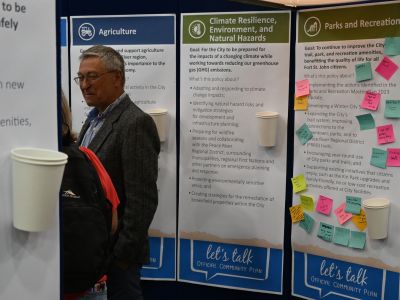 People speak in the City's booth at the Fort St. John Tradeshow in front of several draft goals statements on the wall.