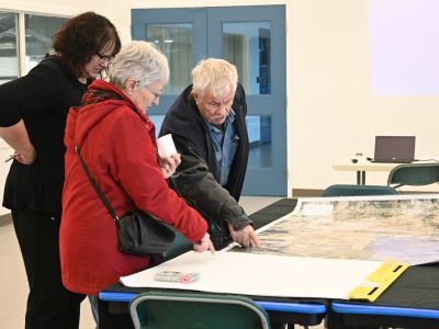 Three people review a map at a Let's Talk OCP open house.